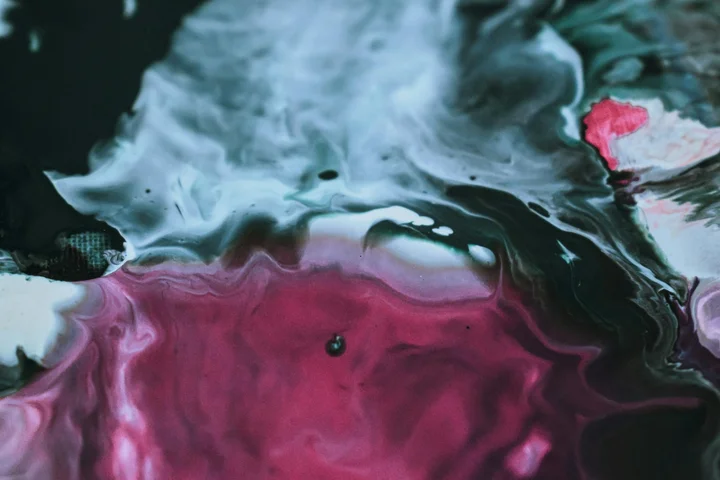 Close-up abstract image of blue and pink paint swirls