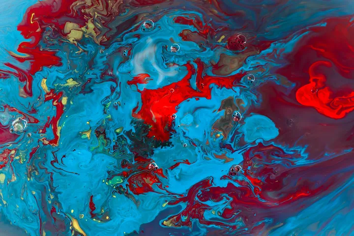 Close-up of colorful abstract paint swirls in red, blue, turquoise, and yellow.