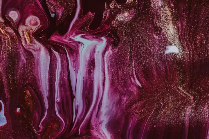Close-up of an abstract marbled pattern in purple, pink, white, and gold tones, resembling liquid stains on a surface.