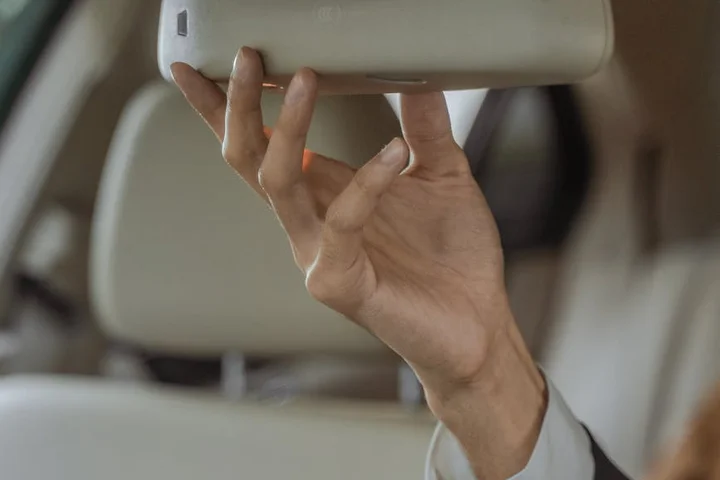 Close-up of a hand gently handling a light-colored Alcantara car interior