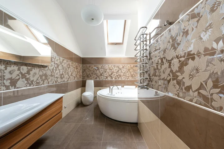 Modern bathroom featuring a corner white bathtub, brown and beige floral-patterned wall tiles, a glass shower screen, and a skylight.