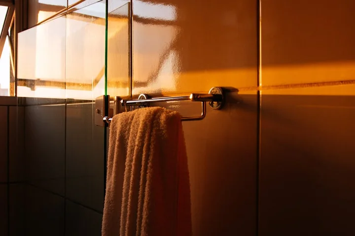 Warm-toned bathroom with a towel hanging on a metal rack, illustrating the final washing stage for treating makeup stains on towels.