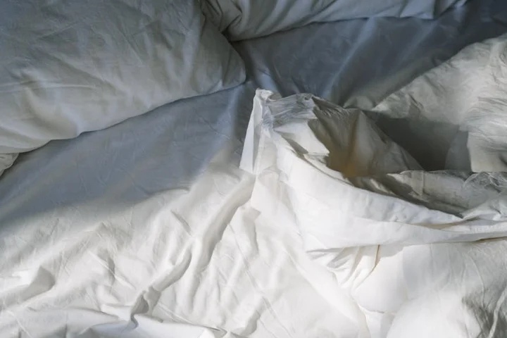 Close-up of white bedding with subtle yellow armpit sweat stains