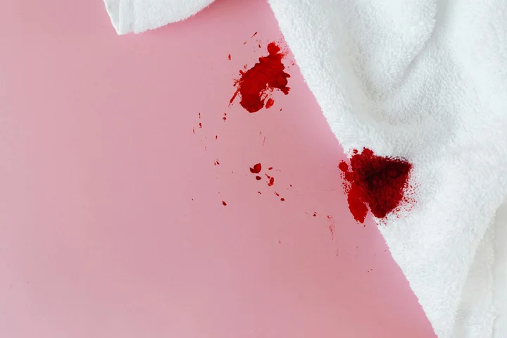 Pink surface with a white cloth and red stains, depicting a stubborn stain being challenged by strong bleaching agents.