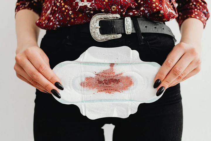 Person wearing dark pants holds a white cloth with a red blood-like stain at the center.