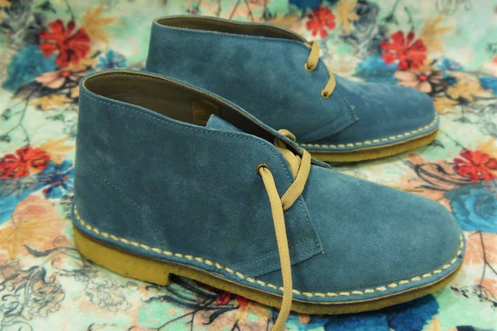 Blue suede shoes on a colorful floral background.