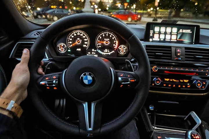 Driver's perspective of a car interior featuring a BMW steering wheel and dashboard.