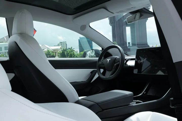 Modern car interior with light-colored seats and a central touchscreen, empty and ready for cleaning supplies.