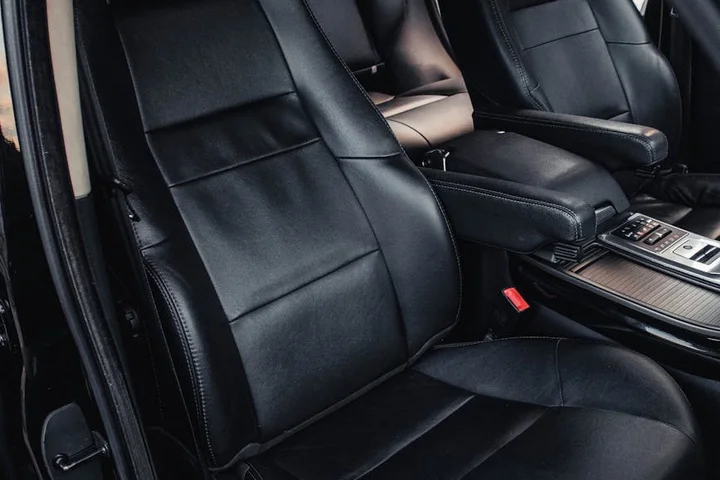 Black leather car seats and center console in a vehicle, ready for stain-removal supplies.