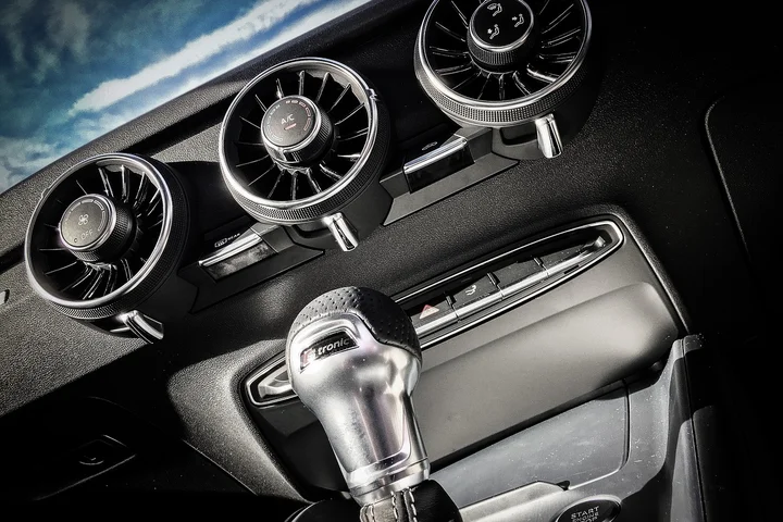 Close-up of a car interior showing three circular air vents and a gear shift knob, illustrating the vehicle's ventilation system.
