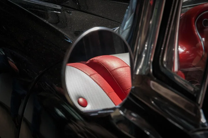 Close-up of a red and white car seat upholstery visible through a side-view mirror.
