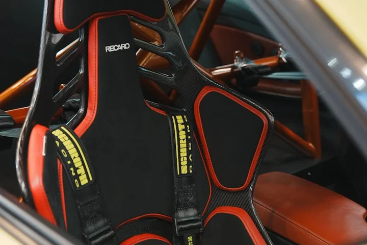 Close-up of a black and red racing car seat inside a vehicle, with RECARO branding visible.