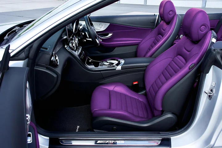 Interior of a car with purple leather seats and a black dashboard, driver’s door open