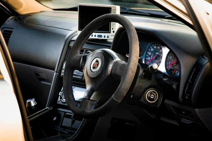 Close-up view of a car's interior, featuring the steering wheel and dashboard.