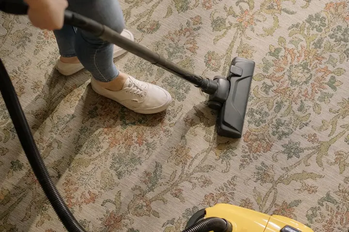 Person vacuuming a patterned carpet.
