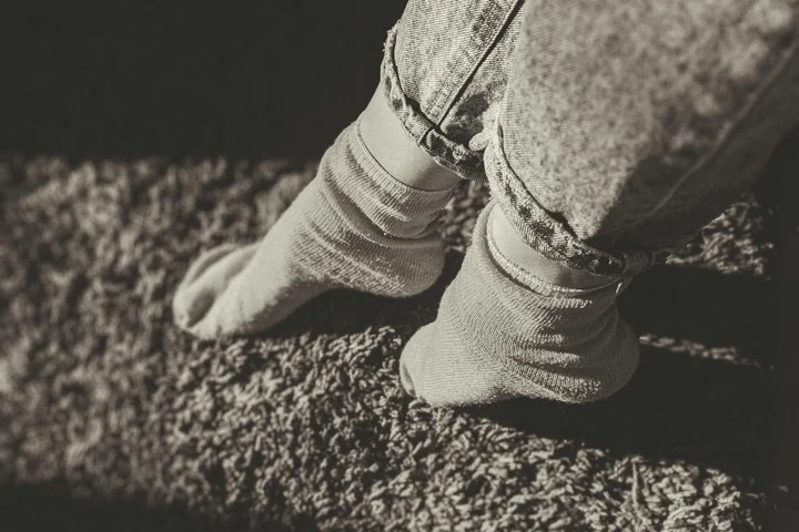 Person wearing light-colored socks standing on a textured carpet