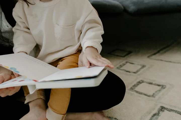 A person sits on a patterned carpet, reading a book; the focus is on the surface being dried to remove stains from carpet padding.