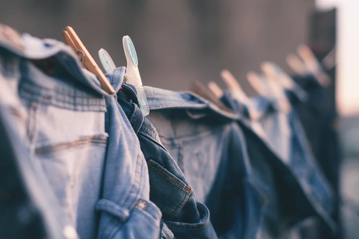 Row of denim jeans hanging on a clothesline with clothespins