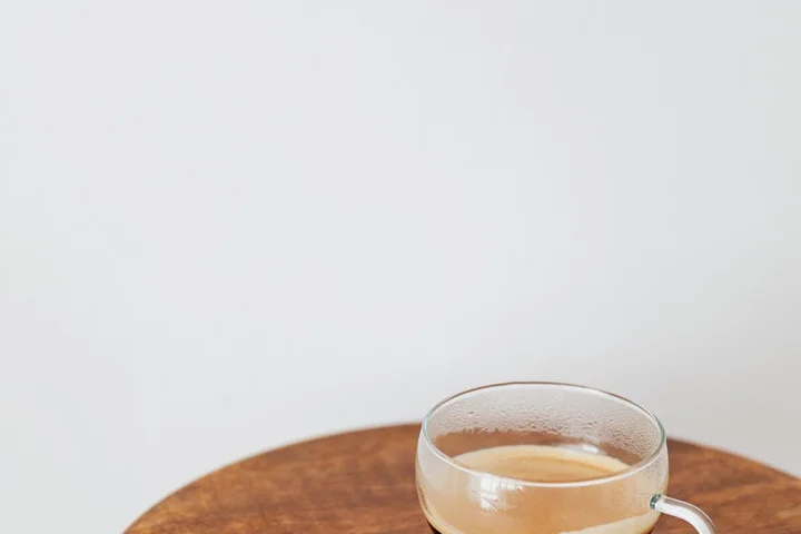 Clear glass coffee cup on a wooden table with a light background.