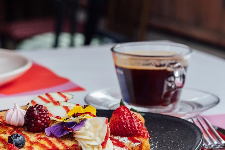 A cup of coffee beside a dessert plate on a table, suggesting common spill scenarios.