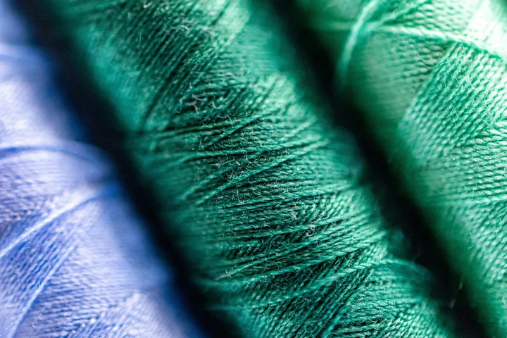 Close-up of blue and green threads on textured spools.