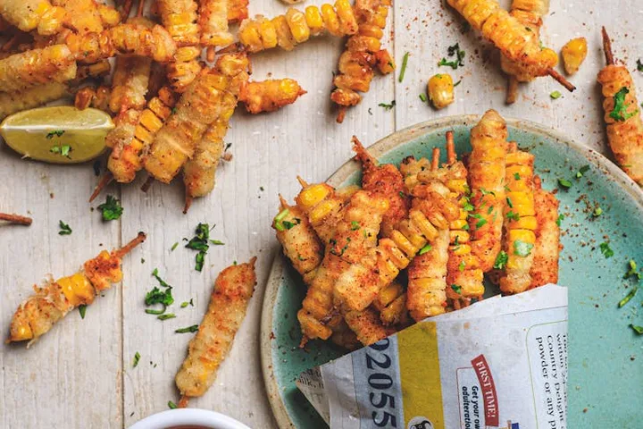 Crispy fried sticks on a blue plate and a light wooden table, garnished with herbs and a lemon wedge.