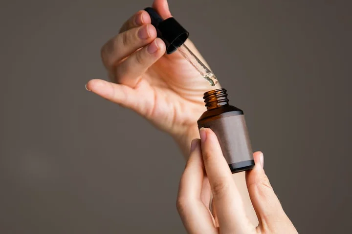 Close-up of hands holding a dropper bottle, about to dispense liquid
