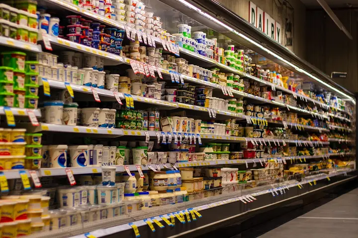 A supermarket dairy aisle filled with shelves of yogurt, milk, and other dairy products.