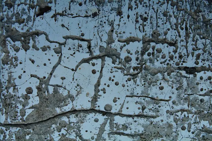 Close-up of a blue-painted wall with cracks and dark stains