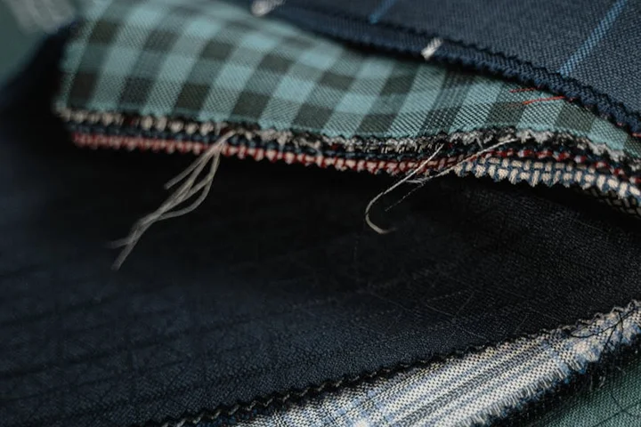 Close-up of stacked fabric swatches including plaid and denim textures, illustrating fabrics affected by diesel stains.