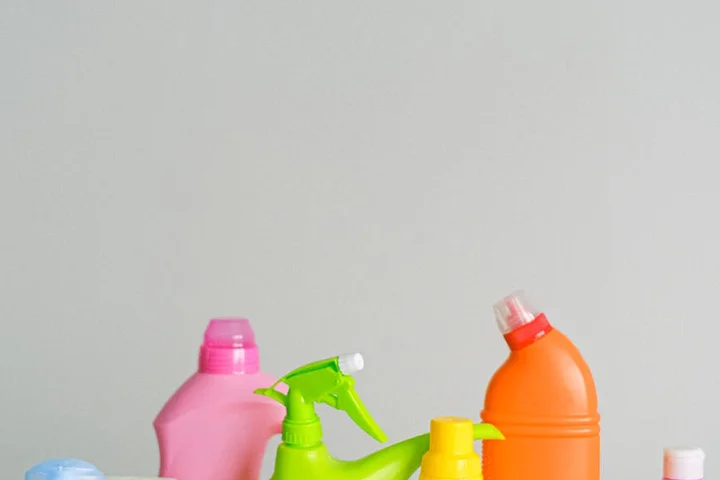 Colorful assortment of household cleaner spray bottles on a light background