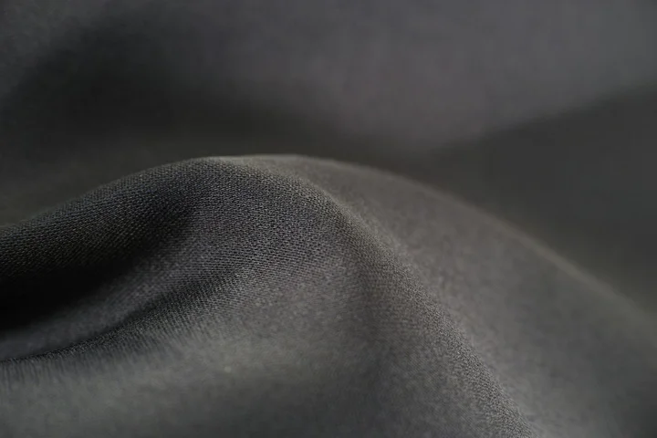 Close-up of dark gray bed linen fabric with subtle wrinkles