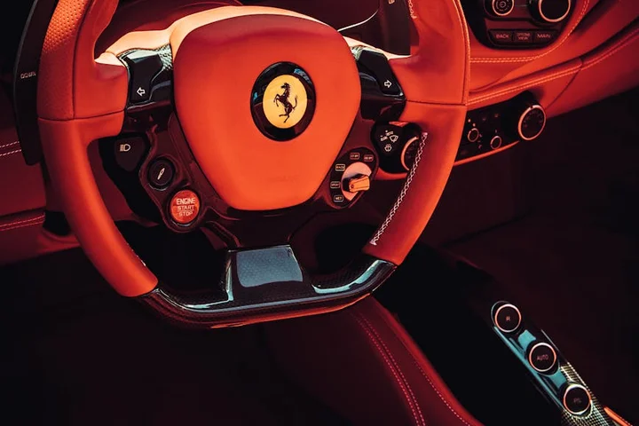 Close-up of a red Ferrari steering wheel with matching red leather interior