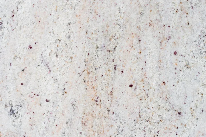 Close-up of a light granite countertop with specks of red, brown, and grey
