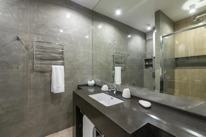 Modern bathroom vanity with a dark granite countertop, sink, and wall-mounted towel racks, illustrating a granite surface.