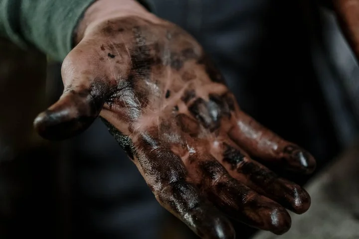 Close-up of a grease-covered hand with dark, oily stains.