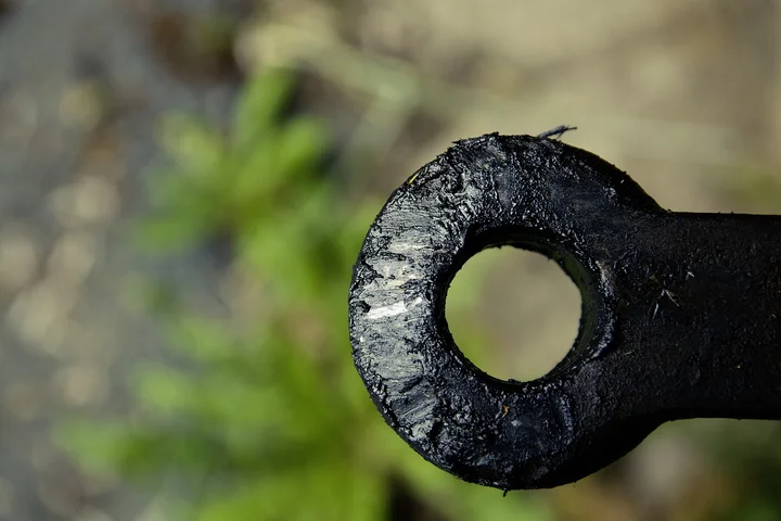 Close-up of a grease-covered mechanical part with a circular hole, illustrating a set-in grease stain scenario.