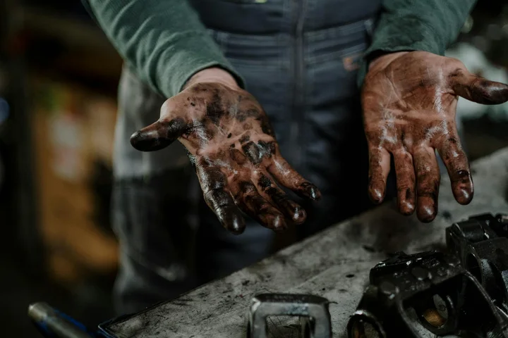 Close-up of dirty hands stained with grease over a workbench