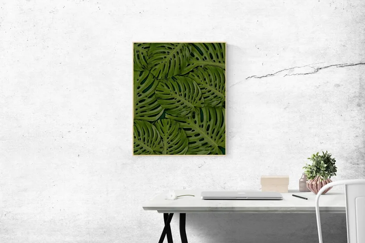 Minimalist white office with a large framed green leaf art piece and a clean desk