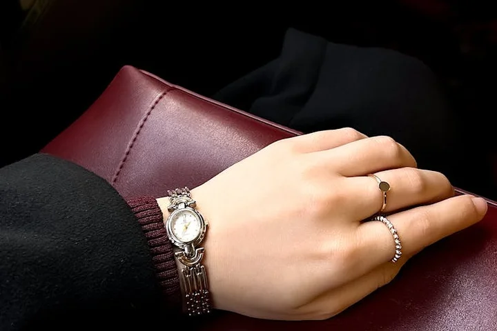 Close-up of a hand resting on a burgundy leather item, wearing a silver bracelet and ring.