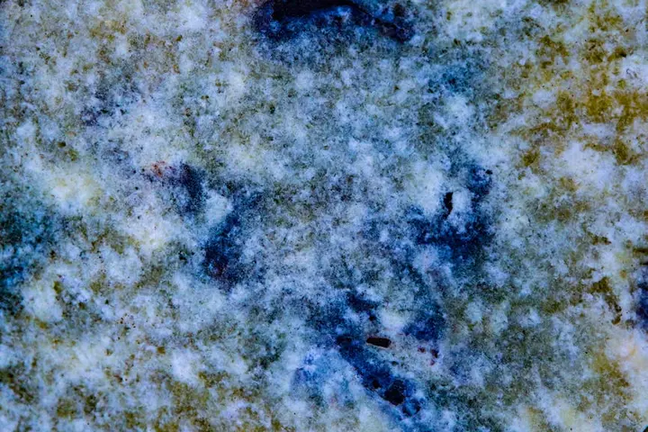 Close-up of a mottled, mineral-streaked surface in blue and white, resembling hard water deposits.
