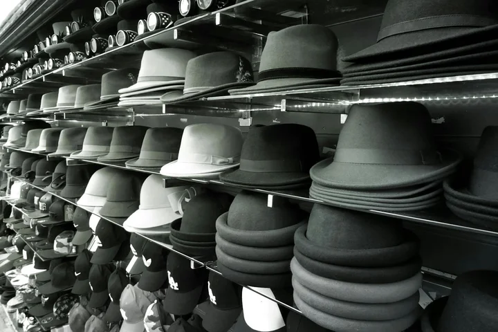 Black-and-white image of hats stacked on shelves in a store display, highlighting different hat materials.