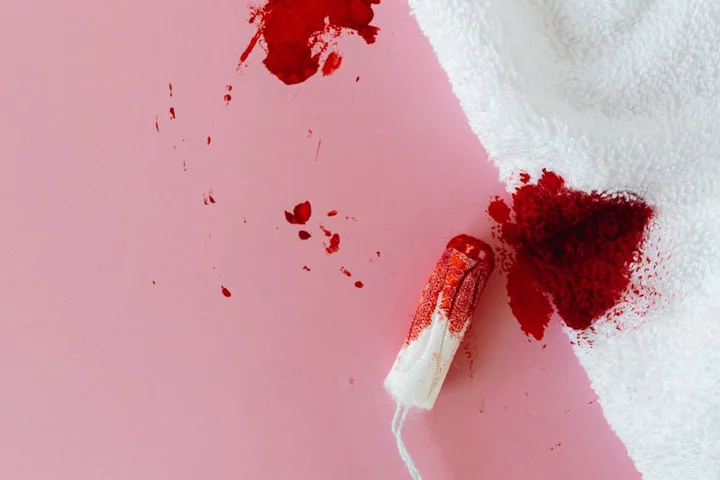Close-up of a red stain on a pink surface with a white applicator, suggesting enzymatic cleaner application.