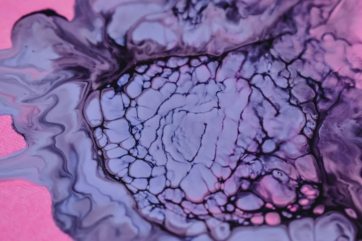 Abstract close-up of purple and pink ink spreading in a marbled pattern