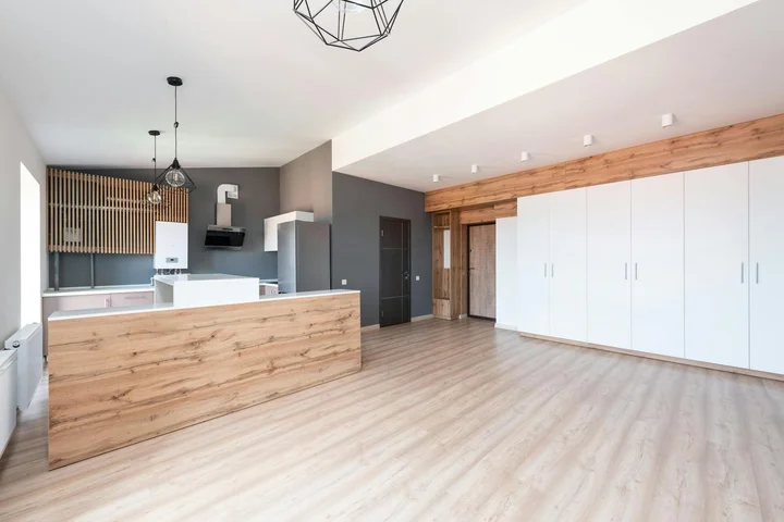 Bright, modern kitchen with an island, light wood flooring, white cabinets, and wooden accents