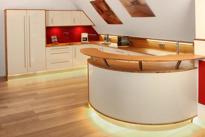 Contemporary kitchen featuring white quartz countertops, a curved island, and warm under-cabinet lighting
