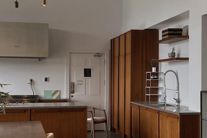 Modern kitchen with warm wood cabinetry, quartz countertops, and a stainless steel sink