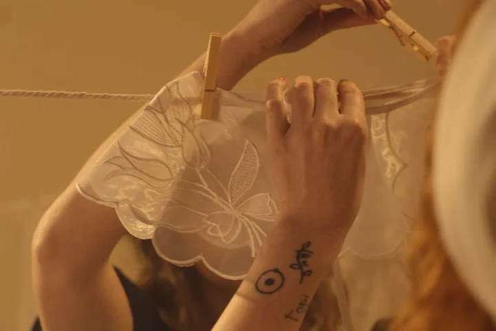 Close-up of a person hanging delicate lace underwear on a clothesline with wooden clothespins.