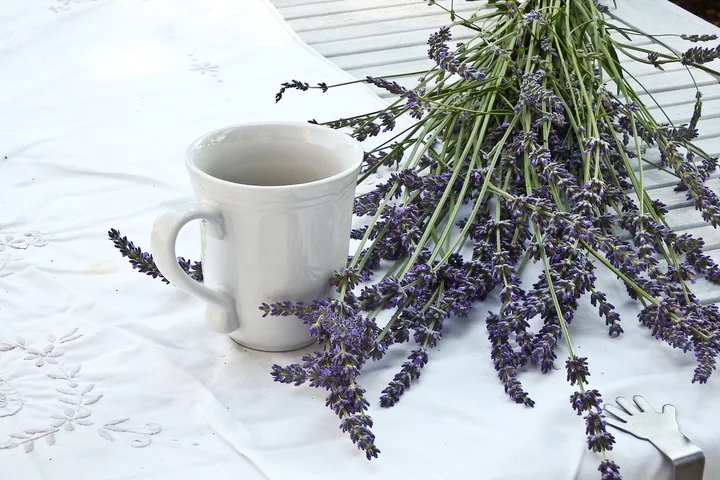 A white tablecloth with a lavender bouquet and a white mug.