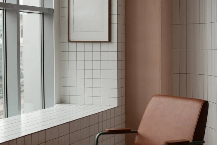 Brown leather chair in a bright, tiled room by a window